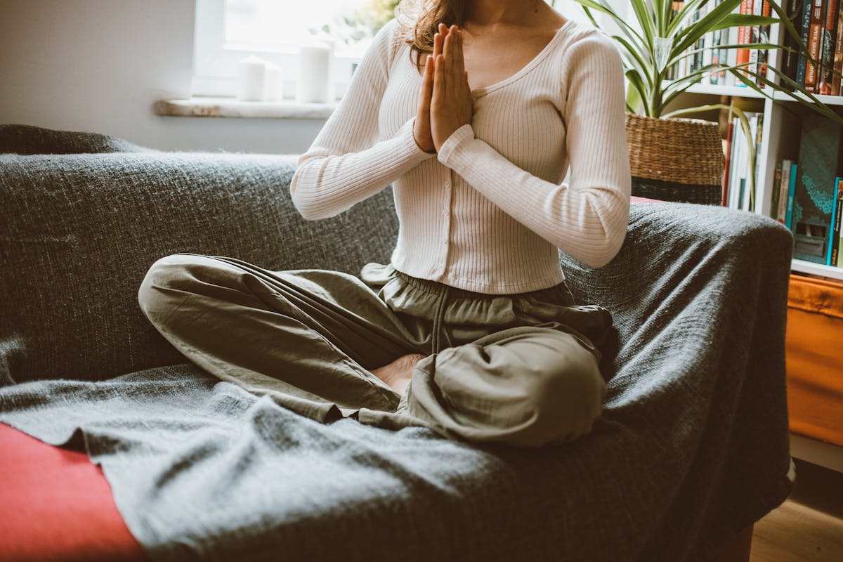 A woman practising yoga in a cosy home interior with warm lighting and natural textures
